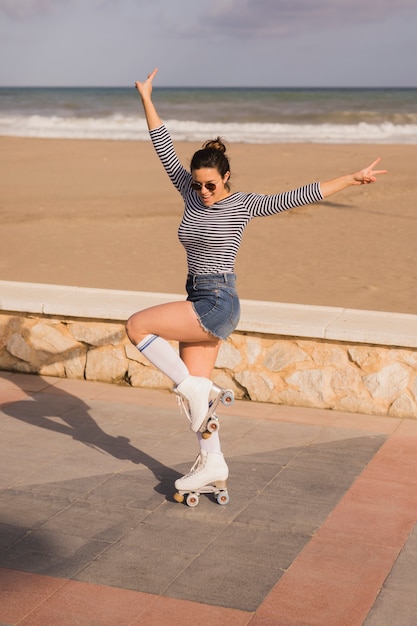 Smiling young woman in roller skate showing peace sign at beach