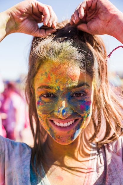 Free Photo smiling young woman's face covered with holi color looking at camera