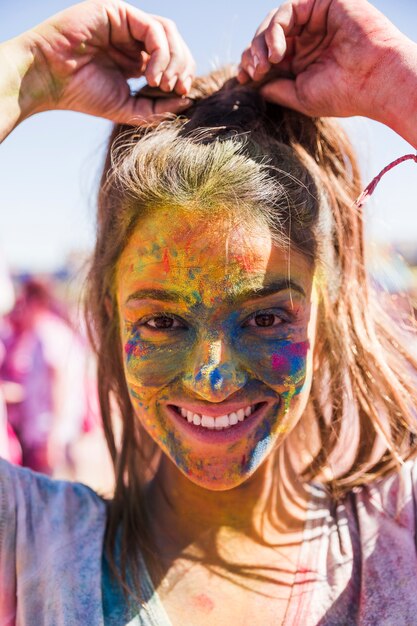 Smiling young woman's face covered with holi color looking at camera