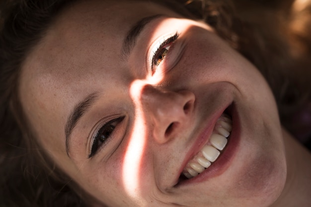 Free Photo smiling young woman in shadow with light gleam