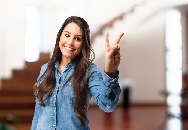 Smiling young woman showing victory gesture