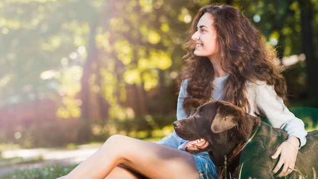 Smiling young woman sitting with her dog in garden