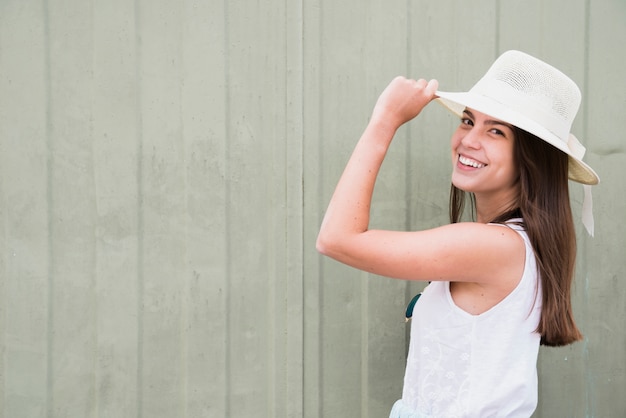 Free photo smiling young woman standing near wooden fence