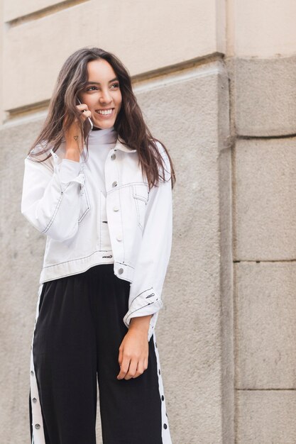 Smiling young woman standing outside talking on mobile phone