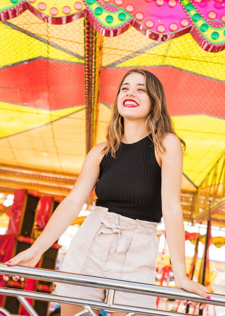 Smiling young woman standing behind the railing in amusement park