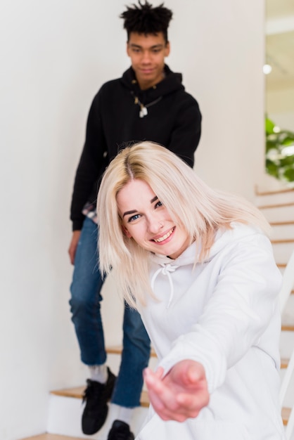 Smiling young woman walking with her boyfriend showing hand toward camera