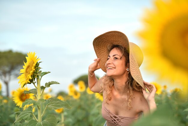 Smiling young woman wearing a hat in the sunflower field