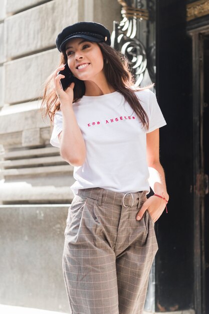 Smiling young woman with hand in her pocket talking on mobile phone