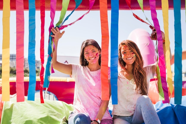 Smiling young women with holi color on their face looking at camera