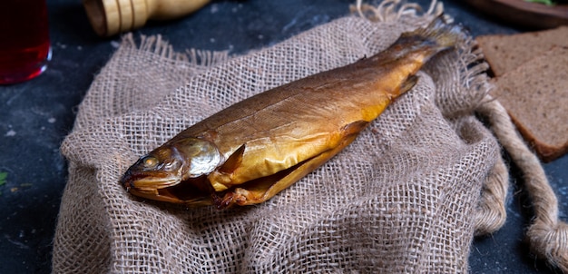 Smoked dry fish on a piece of rustic tissue on the blue table