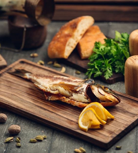 smoked fish on a wooden board with a slice of lemon