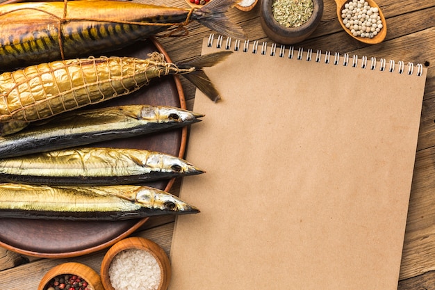 Smoked fishes and notebook top view