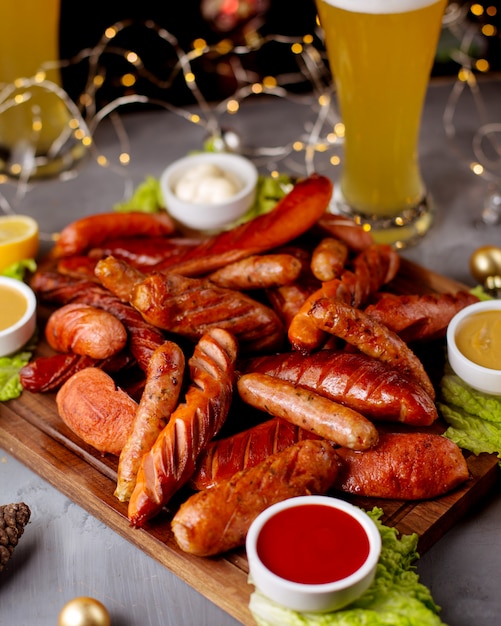 Smoked sausages served with ketchup mustard mayonnaise and glass of beer