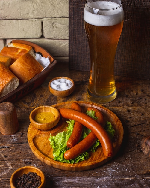 Free photo smoked sausages served with lettuce, mustard and beer