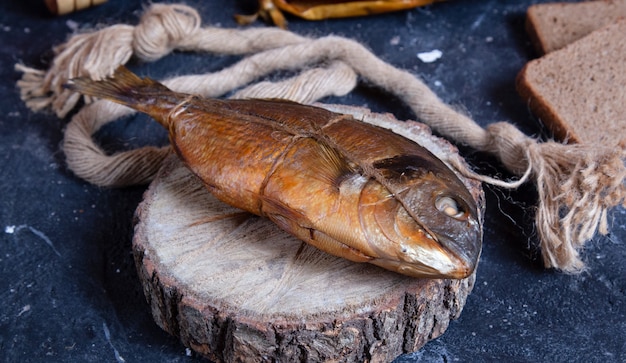 Free Photo smoked whole dry fish on a piece of wood. rustic thread around