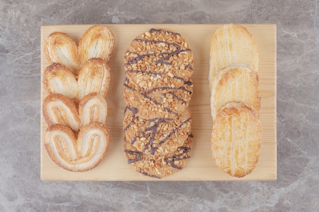 Snack assortment with different cookies on a small board on marble 