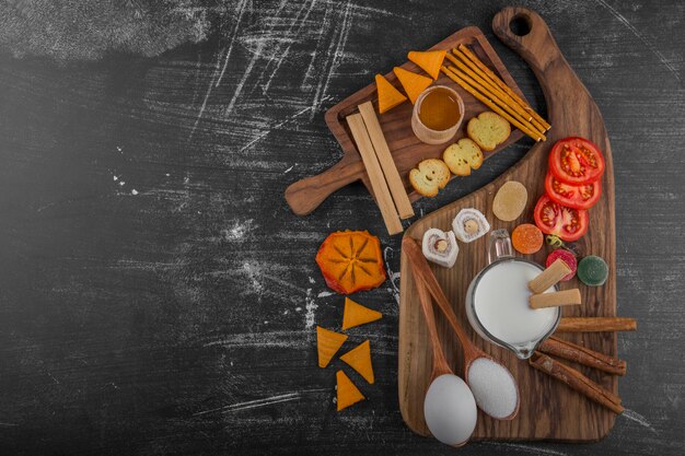 Snack board with chips, crackers and pastries on the wooden platter in the center