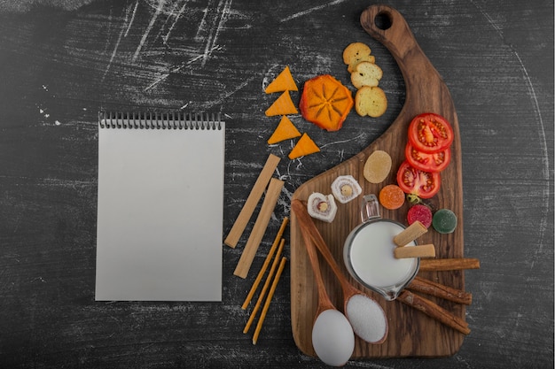 Free photo snack board with crackers and vegetables with a cookbook aside