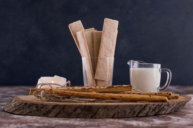 Free Photo snacks and crackers with a glass of milk on a marble table on black.