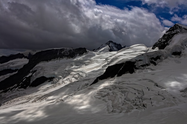 Snow capped mountains under nimbus clouds