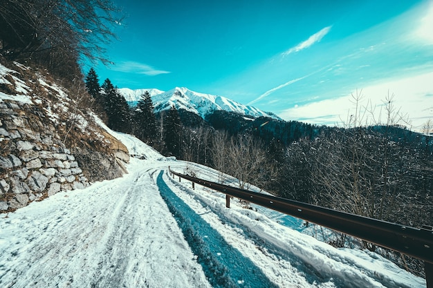 Free photo snow path at the side of a mountain with snow covered mountains