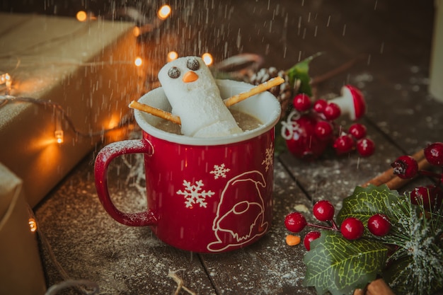 Snowman in the coffee mug under white powder rain