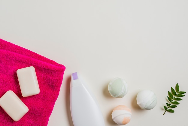 Soap; bath bomb; moisturizer and pink towel with leaves on white background