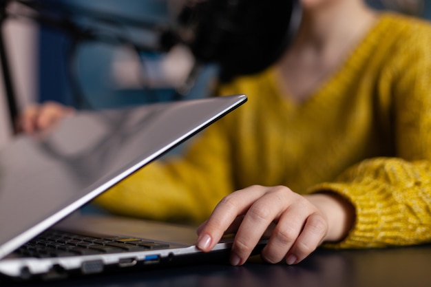 Social media influencer opening laptop talking into professional microphone