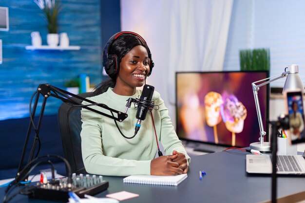 Social media star talking at camera and recording a new episode of show. Speaking during livestreaming, blogger discussing in podcast wearing headphones.