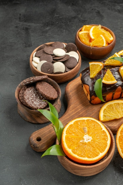 Free photo soft cakes on wooden cutting board and cut oranges with leaves biscuits