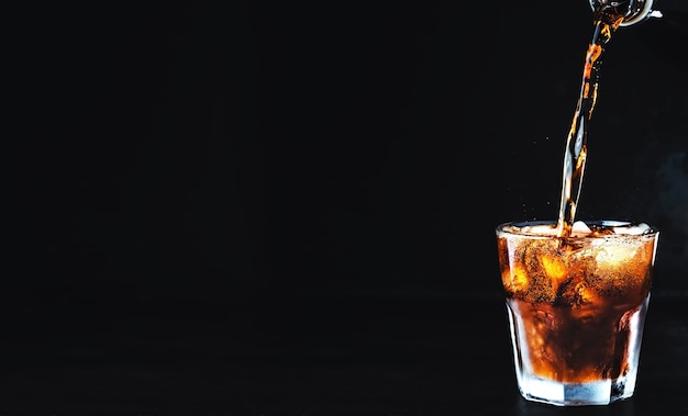 Free photo soft carbonated cola drink is poured into a glass of ice