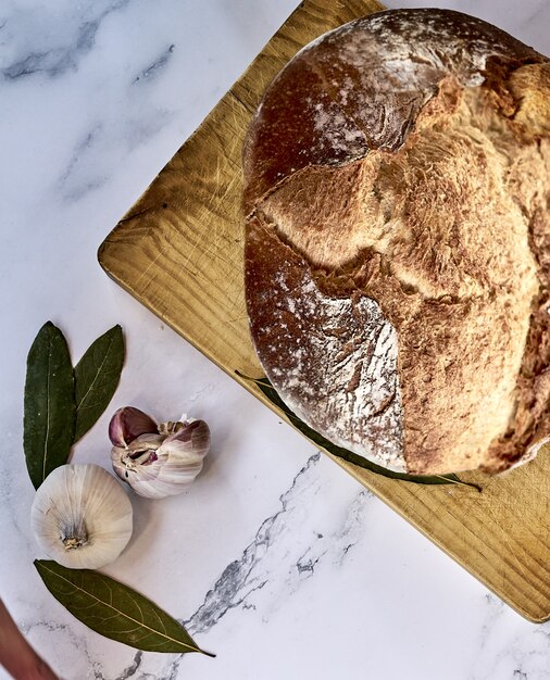 Soft focus of a freshly baked traditional bread on a wooden board with garlic