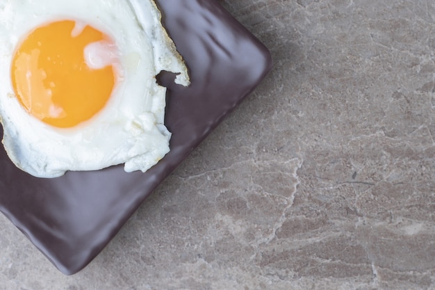 Free photo soft fried egg on dark plate.