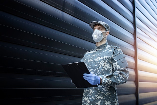 Free photo soldier in camouflage uniform wearing protective gloves and mask in a mission against corona virus