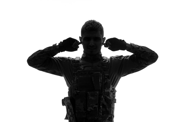 Free photo soldier silhouette serious handsome strong tough army soldier in uniform covering ears