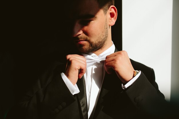 Solid brunette groom in black suit indoor sunlight