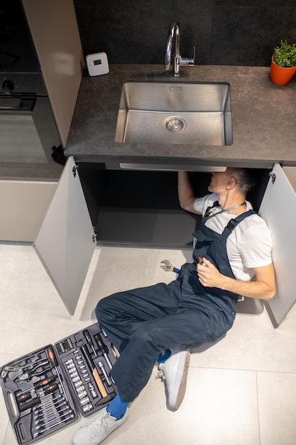 Free Photo solution top view of man plumber in overalls fixing breakdown of sink