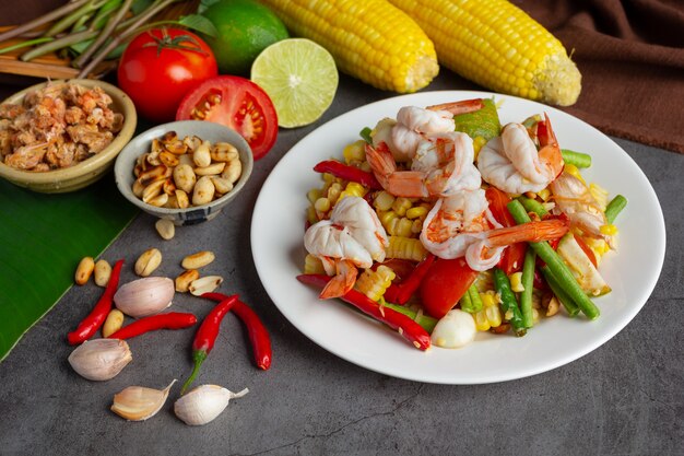 Som Tum with Corn and Shrimp, served with rice noodles and green salad Decorated with Thai food ingredients.