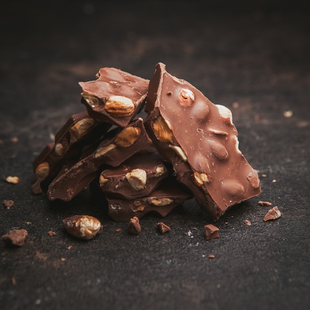 Some almonds with chocolate on dark brown textured, close-up.