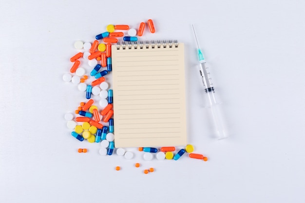 Some colorful pills with notepad and needle