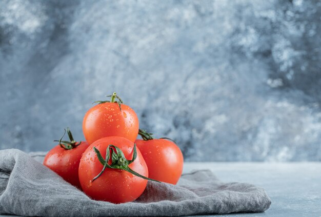 Some of fresh tomatoes on a gray tablecloth . 