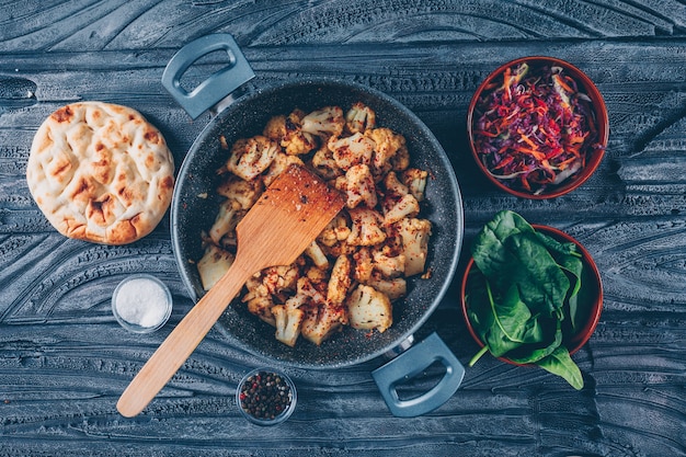 Free photo some fried cauliflower with vegetable salad, green in a pot on dark wooden background, top view.