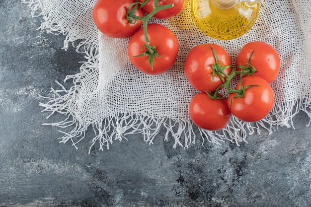 Some juicy tomatoes with a glass bottle of oil.