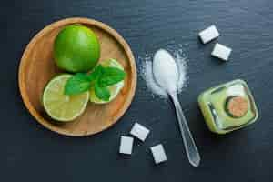 Free photo some lemons with salt, sugar, juice in a wooden plate on dark stone surface, top view.