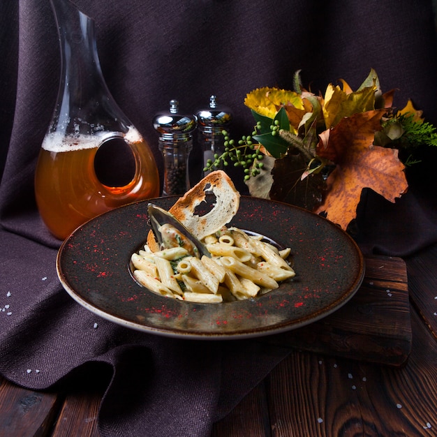 Free photo some macaroni in a black plate on black background with decorations, high angle view.