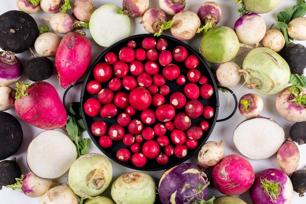 Some of red radishes in a black pan on white red garden radishes