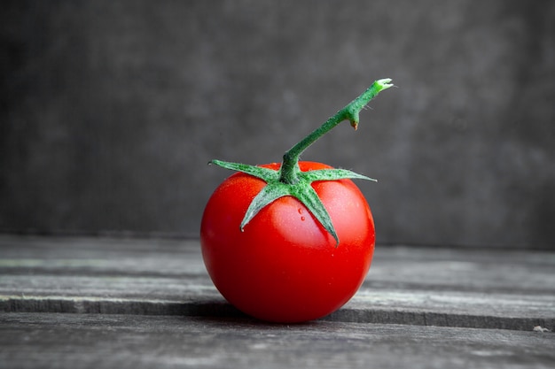 Some tomato on dark wooden and textured background, side view.