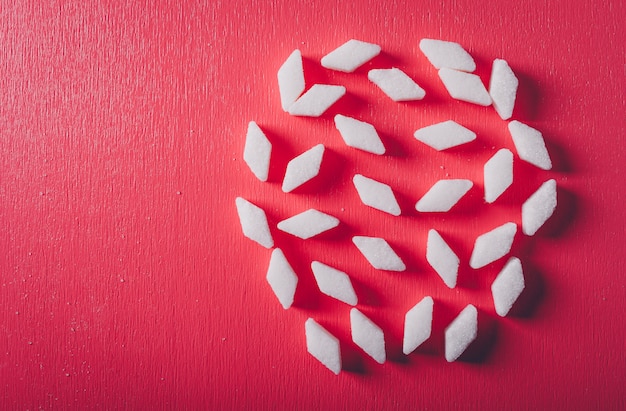 Some white sugar on pink red table, top view.