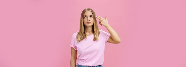 Free photo someone kill me please annoyed and bored fed up cute emotive young woman with tanned skin chubby face and fair hair rolling eyelids holding finger near head as if commiting suicide making shot