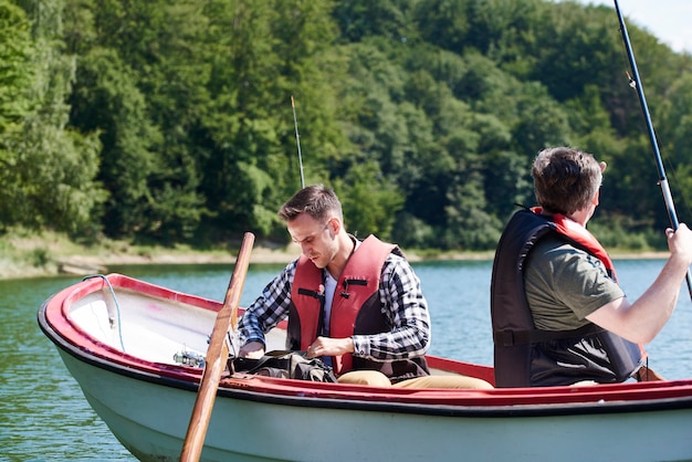 Free photo son and father in boat make preparations for fish